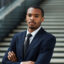 Businessman in lounge Young cross-armed businessman of African-american ethnicity standing by staircase in lounge